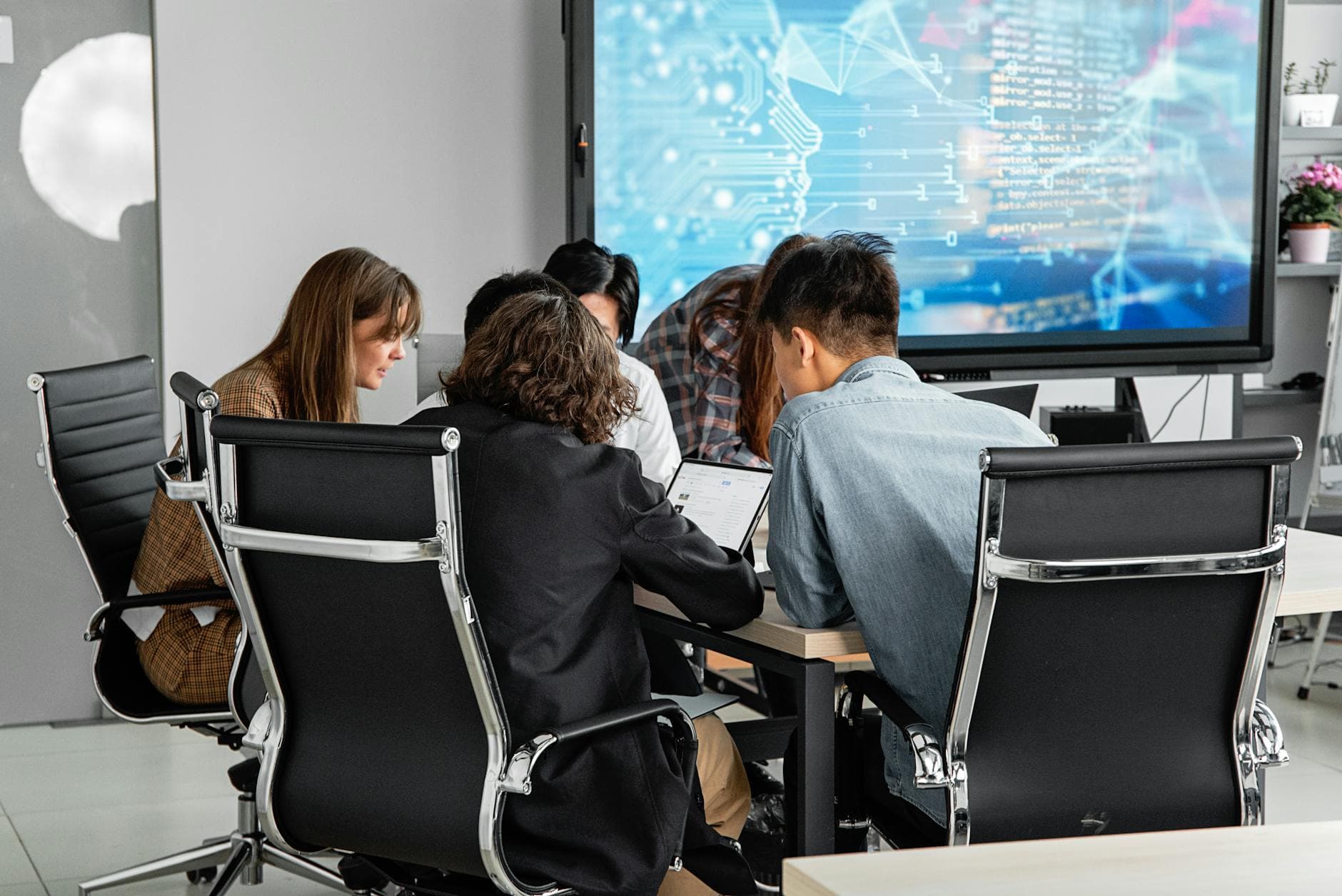 Team collaborating in modern office environment with screens and technology