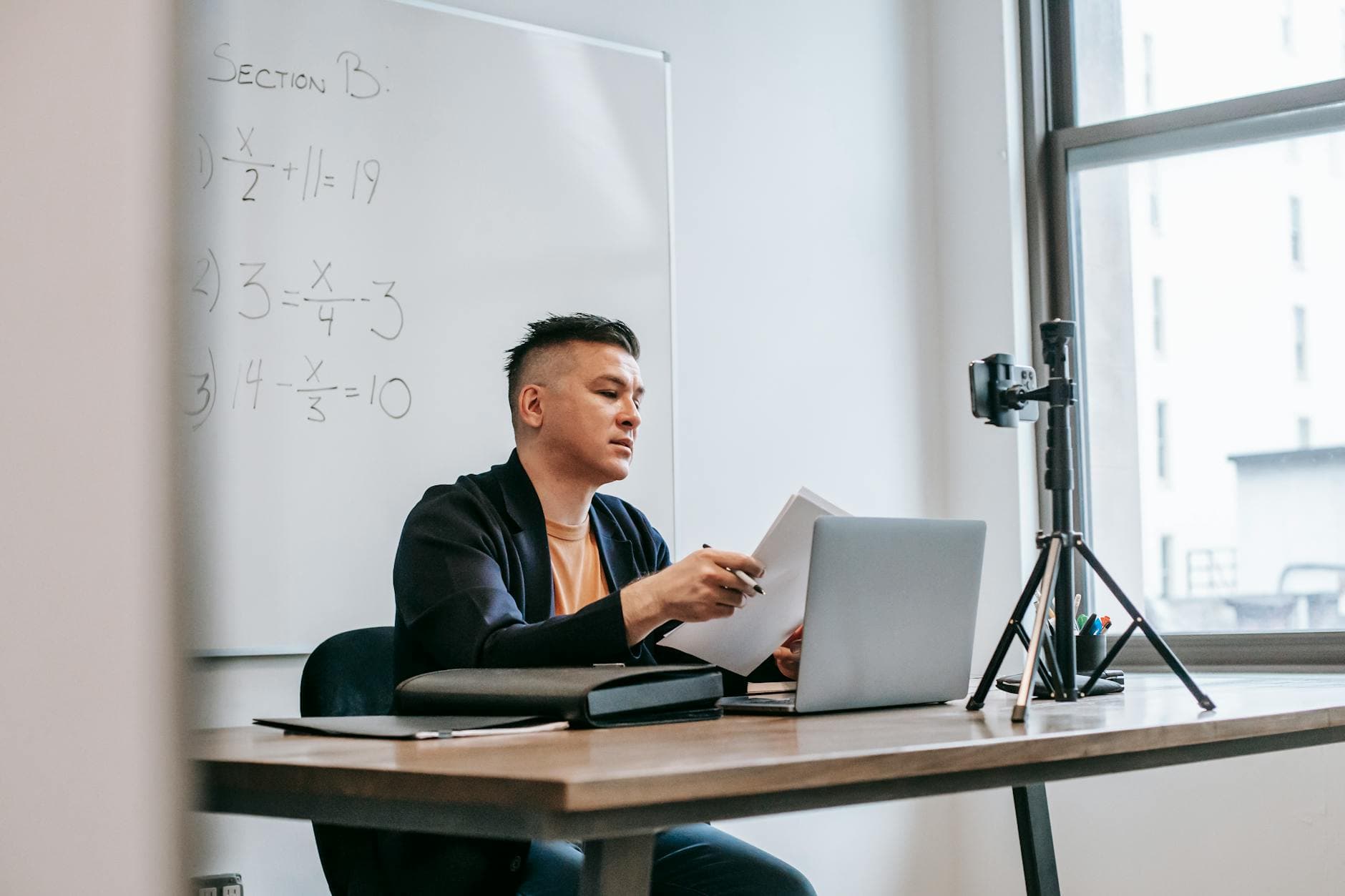 Professional working on laptop with mathematical equations on whiteboard